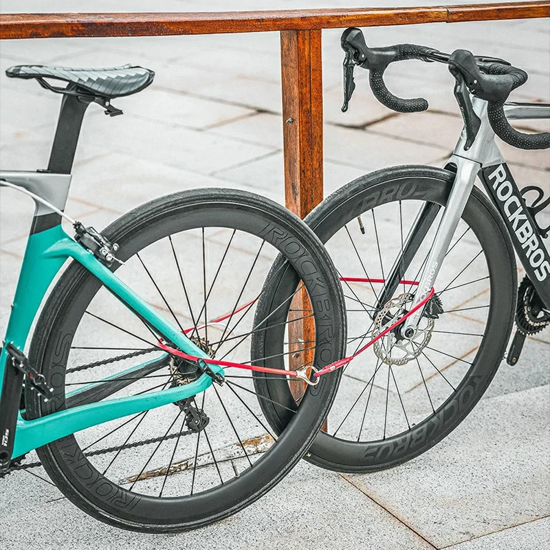 Two bicycles, one teal and one silver with black components, leaning against a wooden railing.