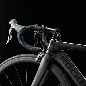 Close-up of a road bicycle frame and handlebar with dark wrapped grips and visible ROCKY branding on the black frame, photographed against a dark background. #Color_Blue