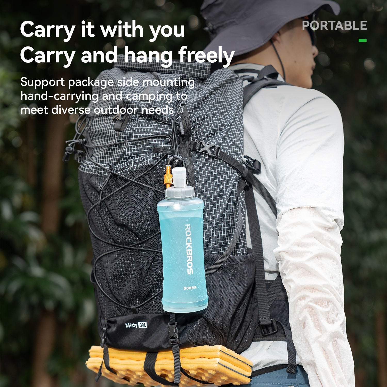 Person wearing a black backpack with a blue water bottle, surrounded by greenery.