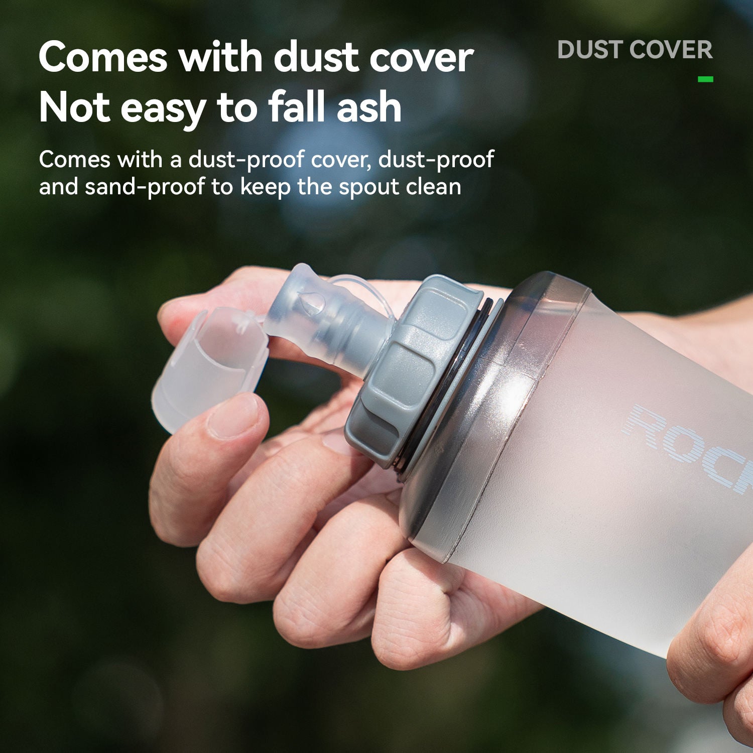 Hand holding a water bottle with a dust cover on a blurred green background
