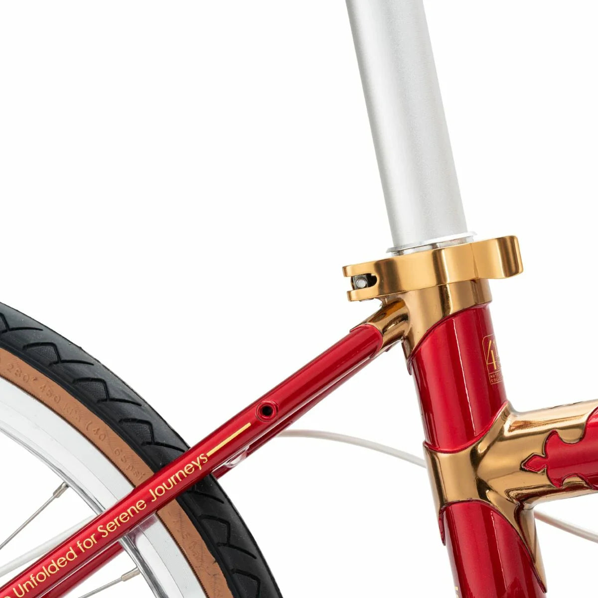 Close-up of a red and gold bicycle frame with 'Unfolded for Serene Journeys' text on a white background. #Color_Red