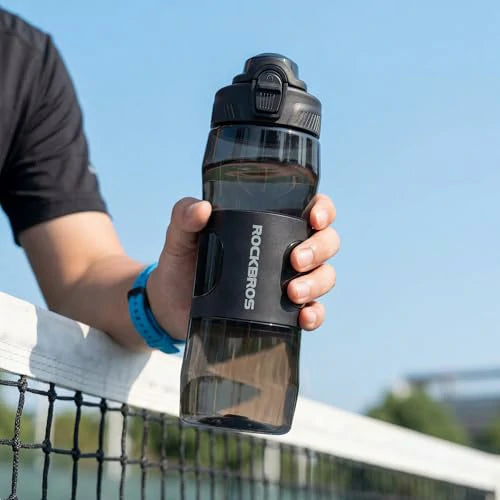 Person holding a black water bottle with 'ROCKEROS' branding on a sports court.