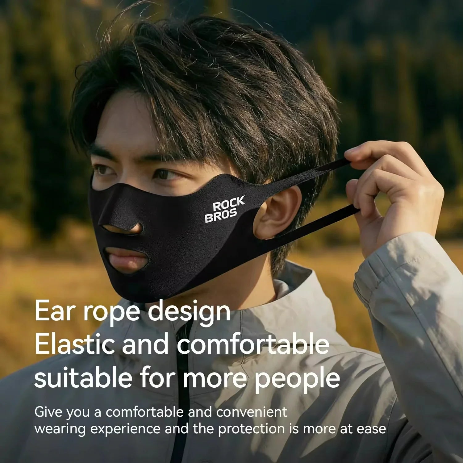 Person wearing a black face mask with ear rope design, set against a blurred natural background.