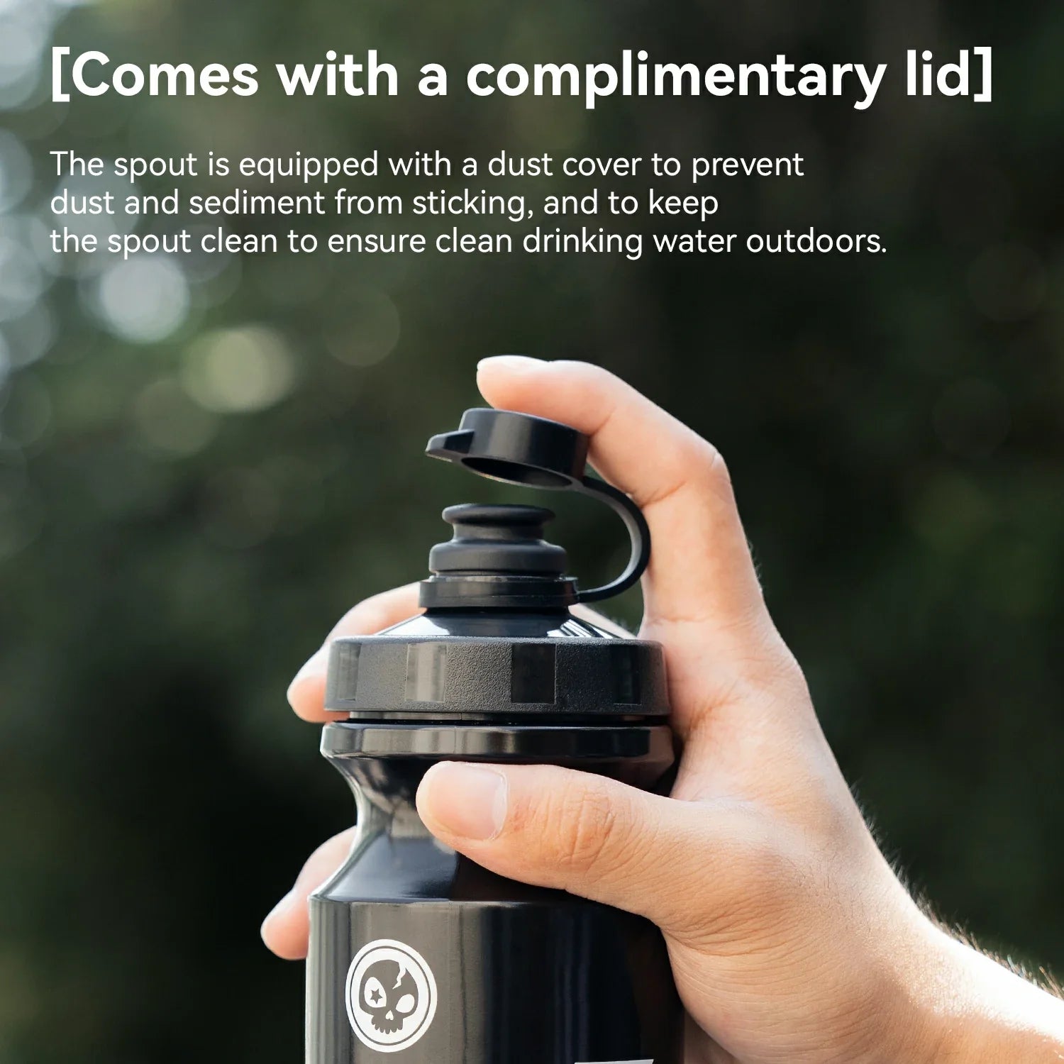 Hand holding a black water bottle with a dust cover on a blurred green background