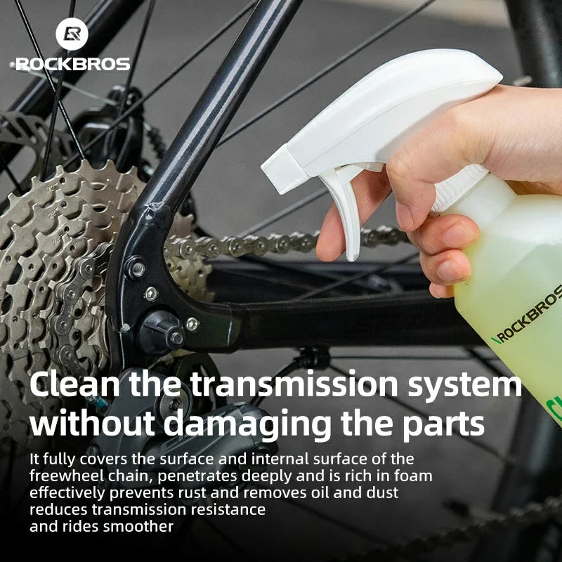 Person cleaning a bicycle transmission system with a spray bottle labeled 'RockBros'.