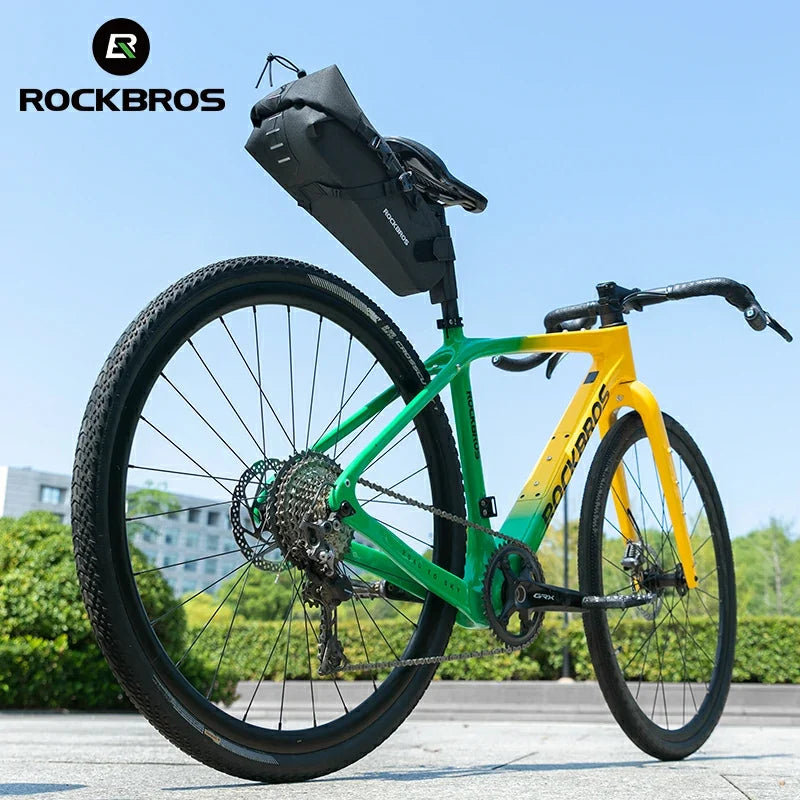 Green and yellow bicycle with a black bag on a clear sky background, featuring the RockBros brand.