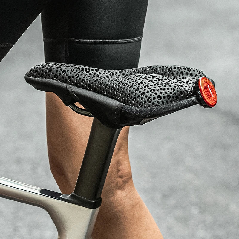 Close-up of a bicycle seat with a textured surface and red element, blurred background