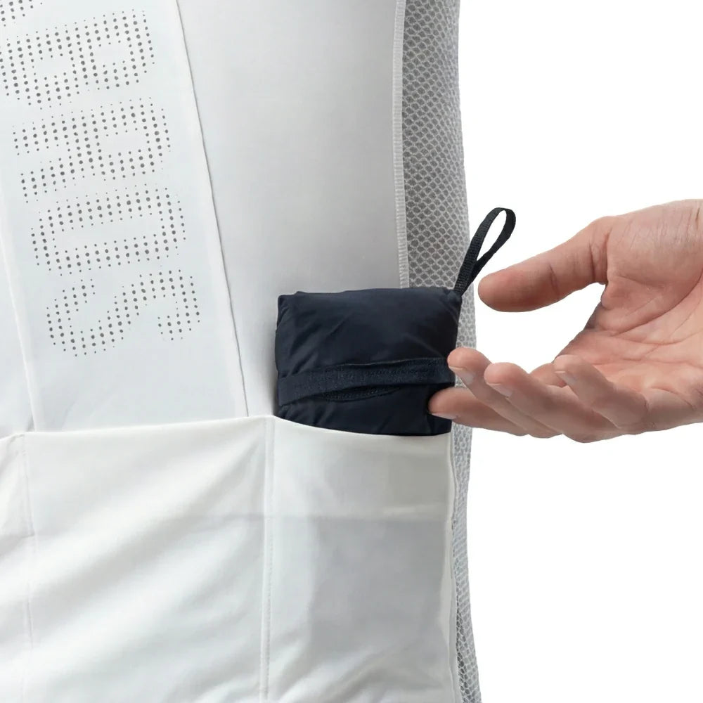 Hand placing a small black item into a white garment with mesh detailing.