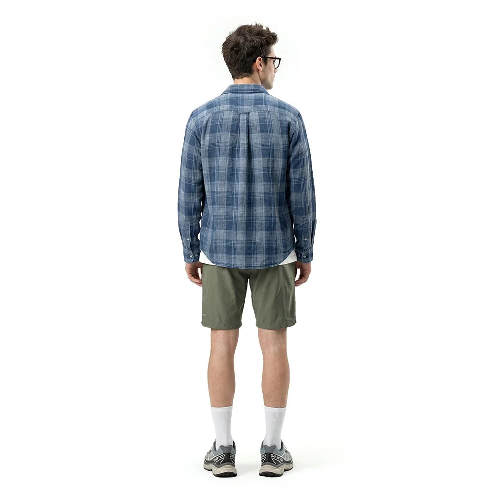 Man wearing a blue plaid shirt and green shorts on a white background