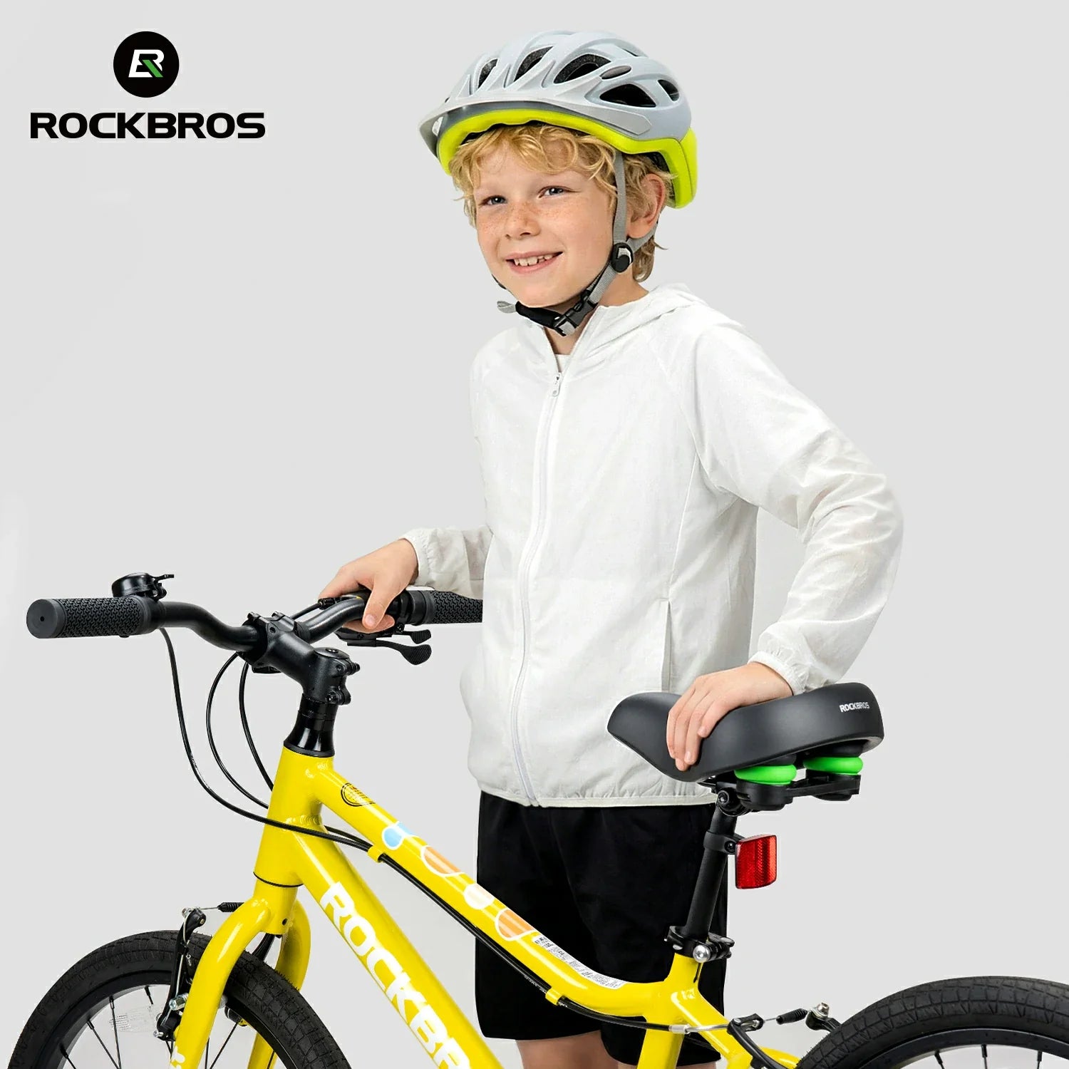 Child with a yellow bicycle wearing a helmet on a plain background, featuring the RockBros brand.