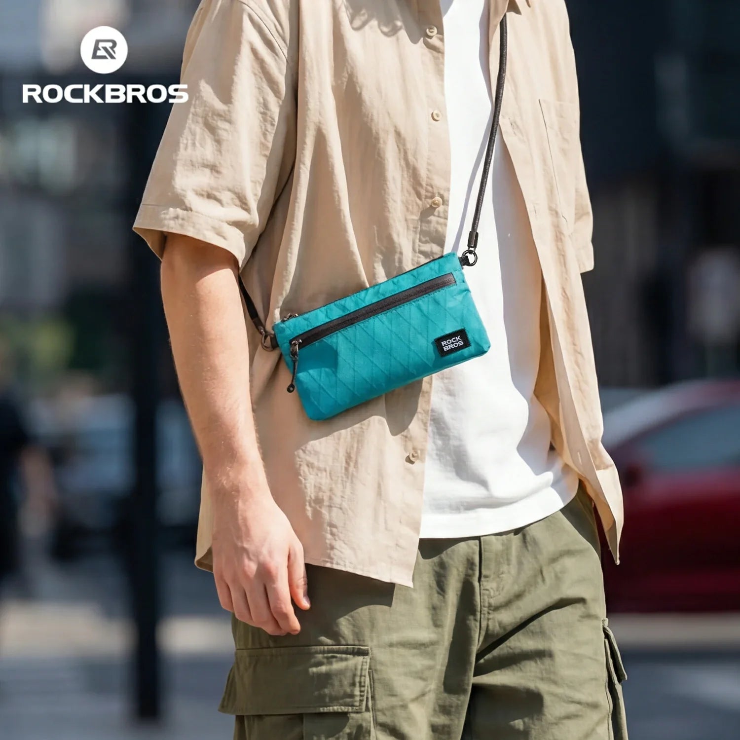Person wearing a turquoise crossbody bag with 'Rockbros' branding, standing outdoors.