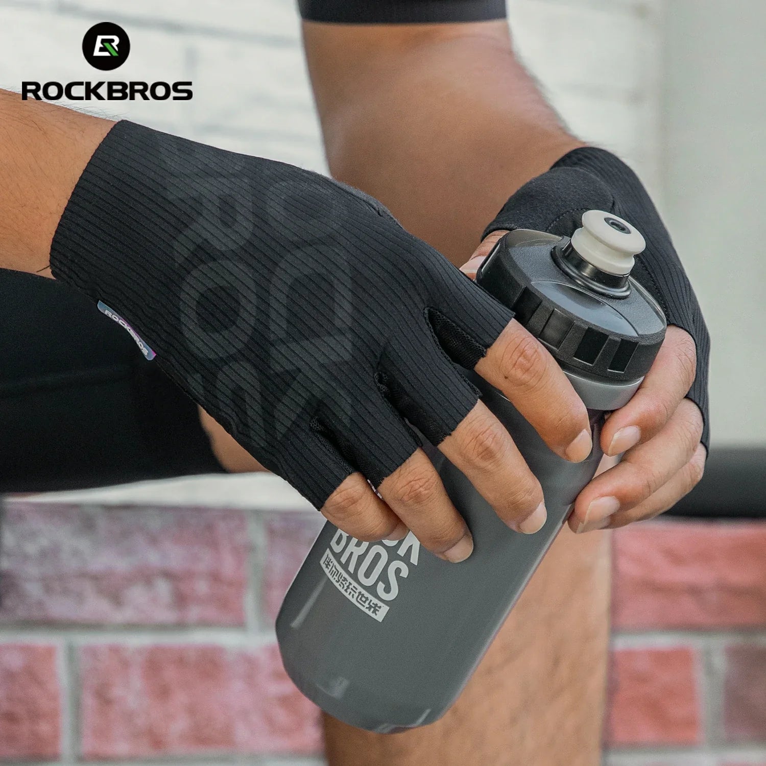 Person holding a gray water bottle with 'RockBros' branding, wearing a black glove.#color_Black