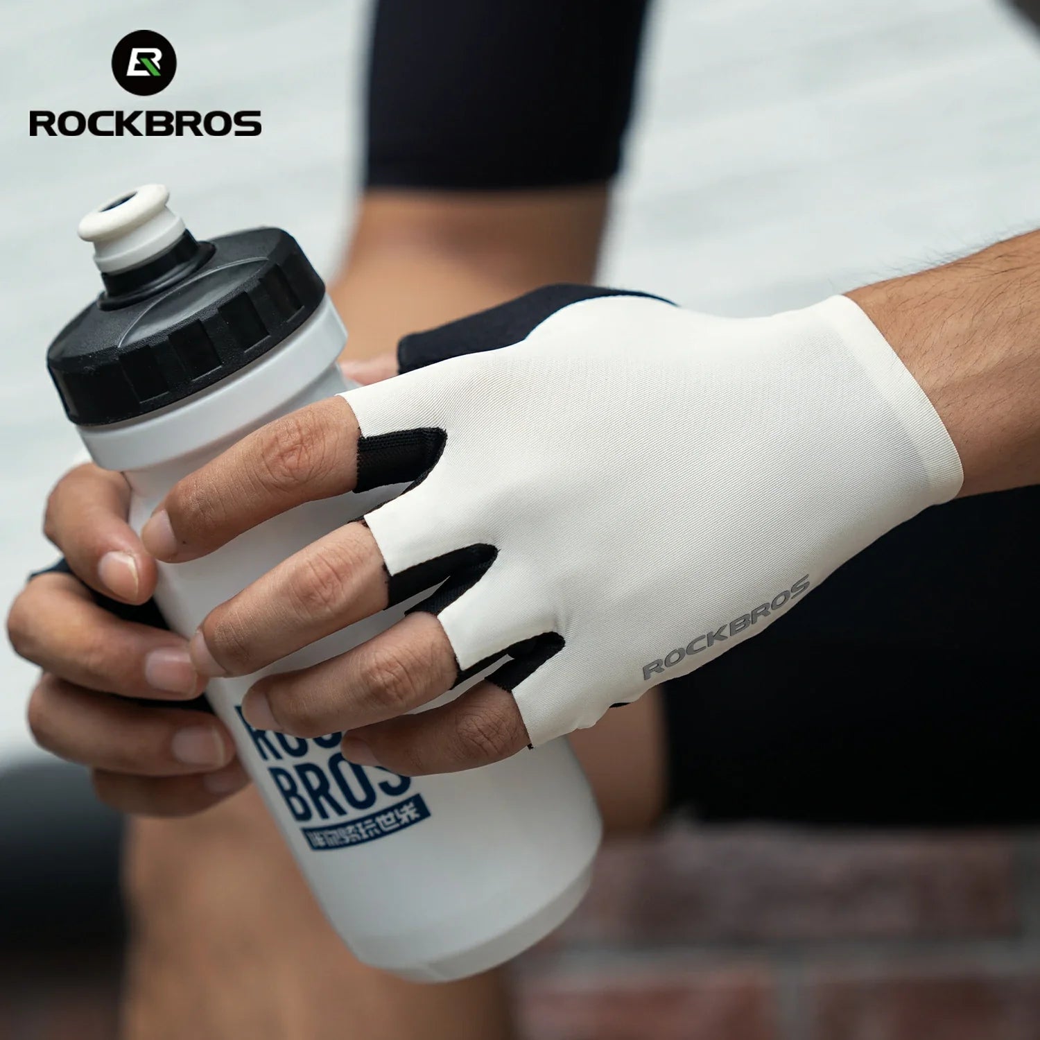 Person holding a white and black water bottle with a glove, wearing a white glove with 'RockBros' branding. #color_white