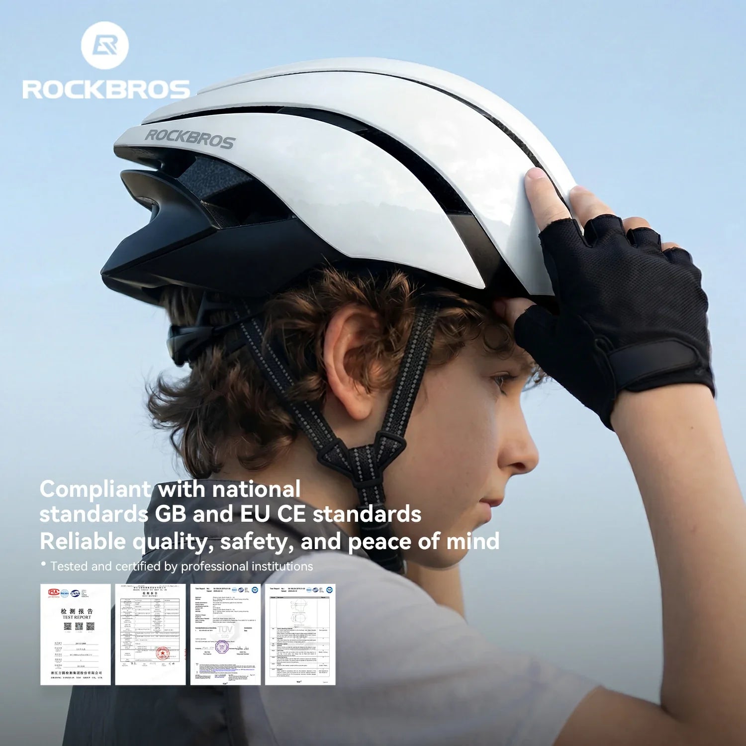 A child wearing a white and black ROCKBROS cycling helmet, adjusting the strap with a black glove, set against a soft blue sky background with product text and certification logos.