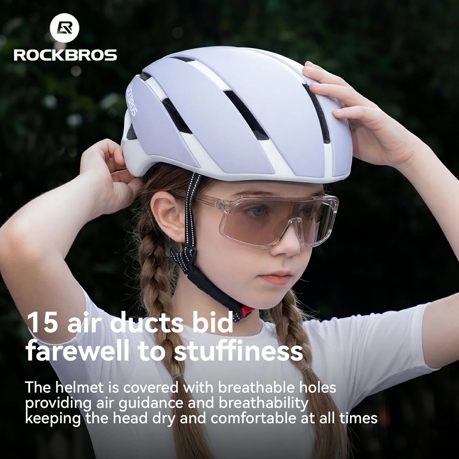 A child wearing a light gray and white ROCKBROS cycling helmet with clear safety goggles, adjusting the helmet straps against a dark green outdoor background. White promotional text overlays are present on the left.