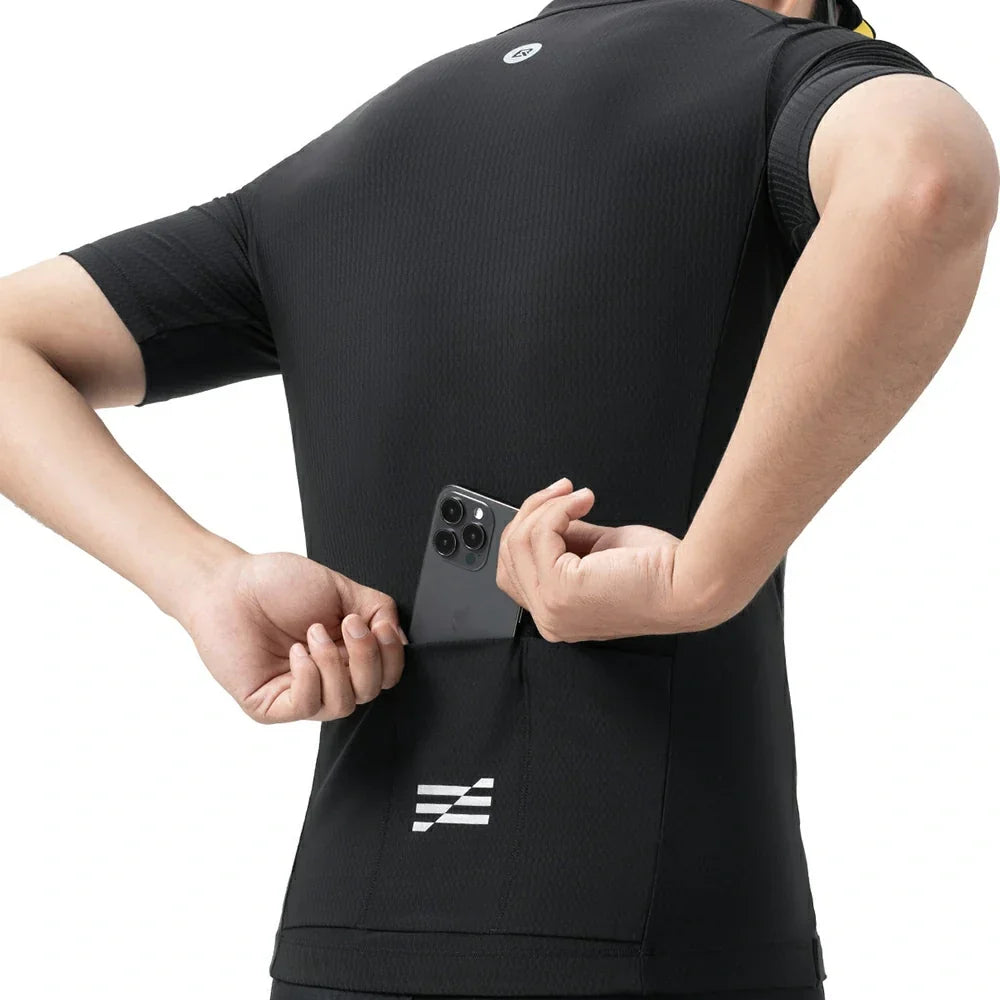 A close-up back view of a person wearing a black short-sleeve athletic jersey with a small white logo near the lower back and a phone tucked into the back pocket. #Color_Black
