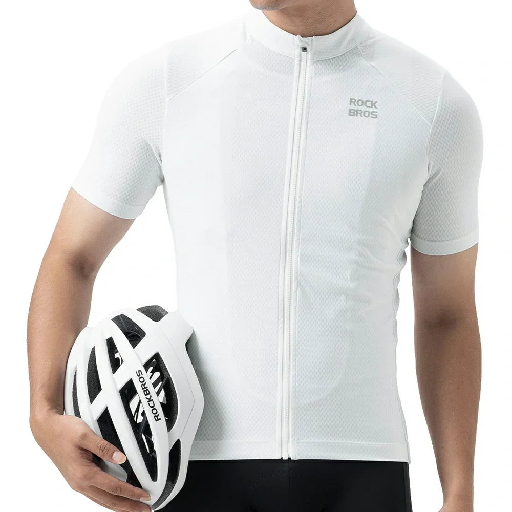 A man wearing a white short-sleeve cycling jersey with a full zipper and a small gray ROCKBROS logo on the chest, holding a white and black cycling helmet against a clean white background. #Color_White