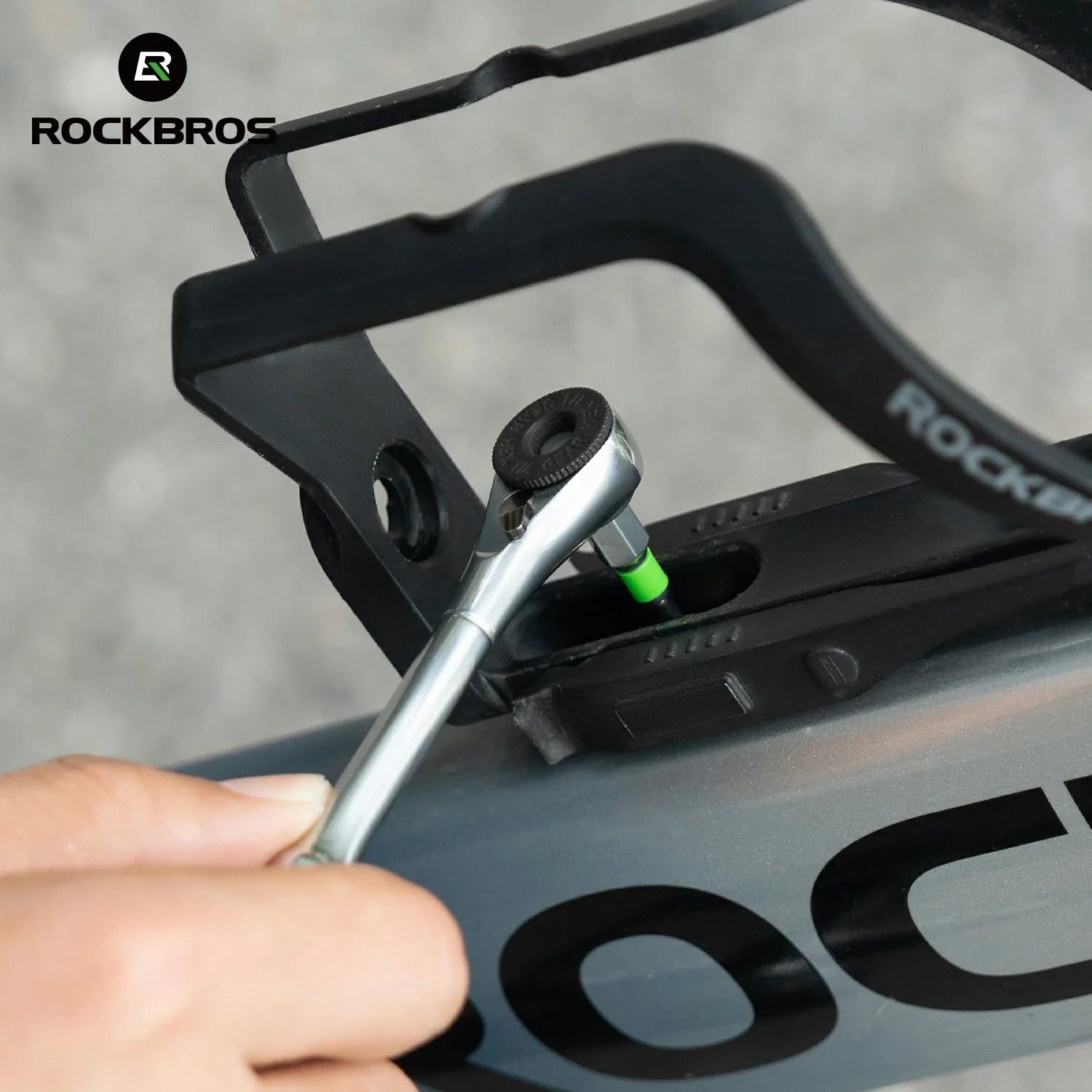 Person using a tool to adjust a black bike component with 'RockBros' branding.