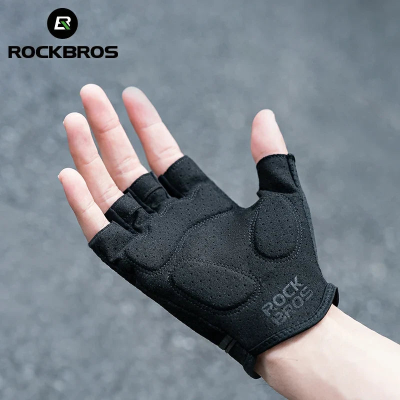 Black half-finger glove on a hand with a gray background, featuring the RockBros brand.  #color_black