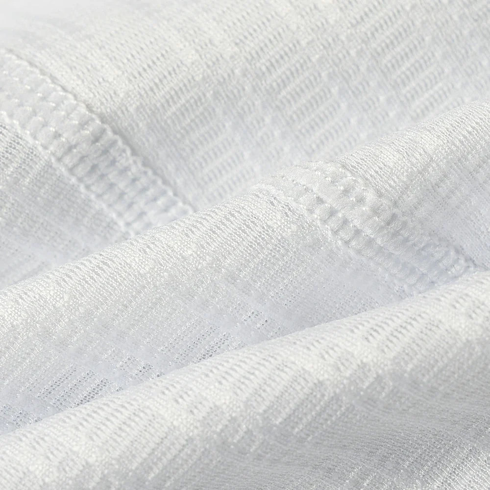 A close-up of white textured fabric with a fine ribbed pattern and soft folds.