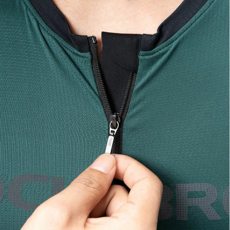 Person zipping a green athletic outfit with a brand logo. #Color_Green