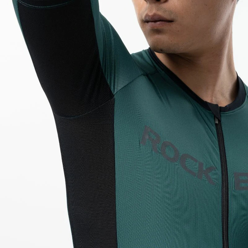 Person wearing a teal and black cycling outfit with 'Rock' branding. #Color_Green