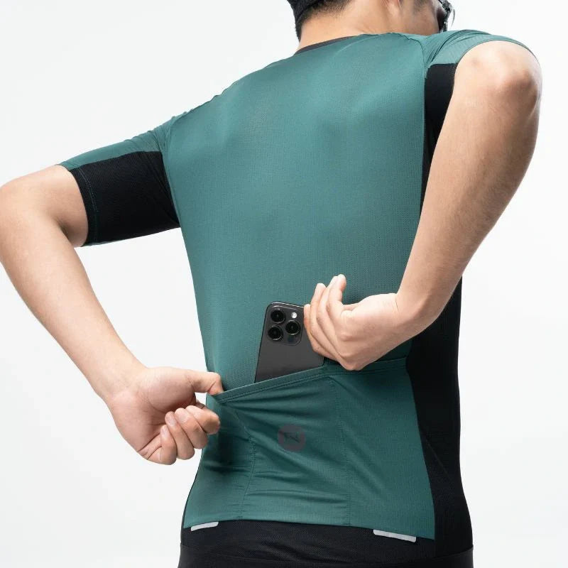 Person wearing a green athletic shirt with a phone pocket, holding a phone. #Color_Green