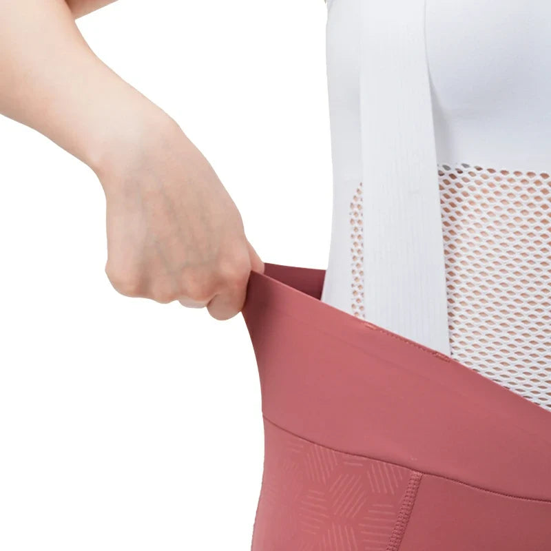 Person wearing a white top with mesh detail and pink pants, adjusting the waistband. #color_Pink