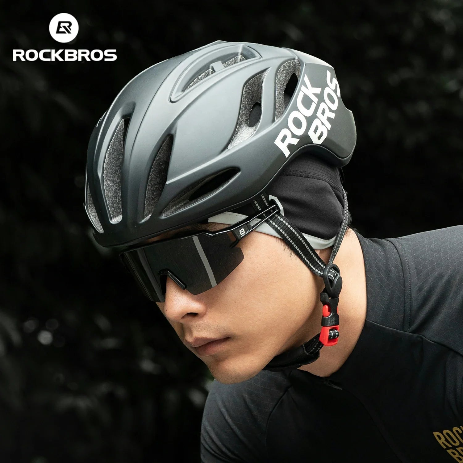 Person wearing a gray ROCKBROS helmet with sunglasses on a dark background